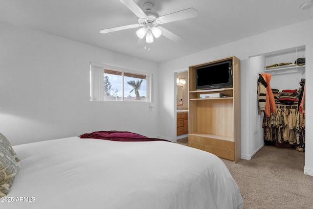 bedroom with light colored carpet, ceiling fan, ensuite bathroom, a walk in closet, and a closet