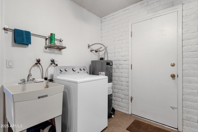 laundry room with laundry area, brick wall, a sink, water heater, and washer / clothes dryer