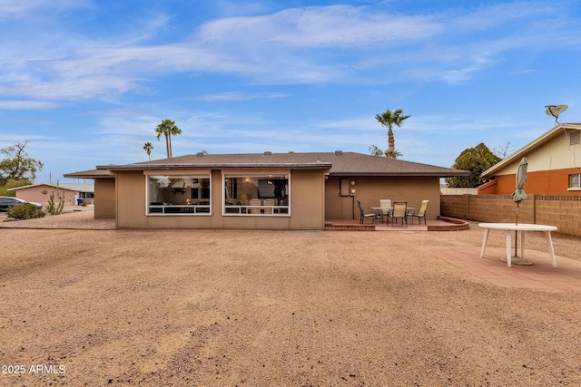 rear view of house featuring a patio area, fence, and stucco siding