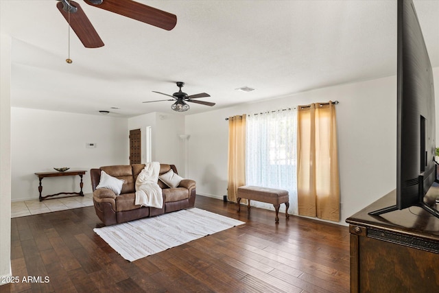 living room featuring hardwood / wood-style flooring, ceiling fan, and a wood stove