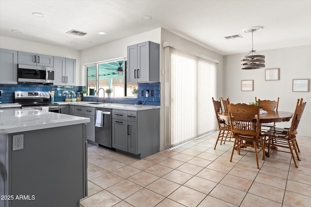 kitchen featuring gray cabinetry, backsplash, and stainless steel appliances