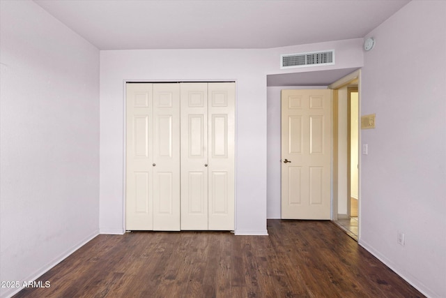 unfurnished bedroom with dark hardwood / wood-style flooring and a closet