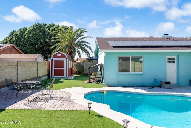 rear view of house featuring a patio, a yard, a shed, a fenced in pool, and solar panels