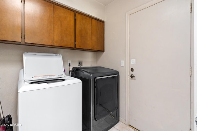 clothes washing area with cabinets, light tile patterned floors, and washing machine and clothes dryer