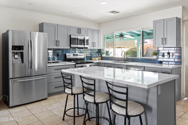 kitchen featuring a kitchen island, appliances with stainless steel finishes, sink, a kitchen breakfast bar, and light tile patterned floors