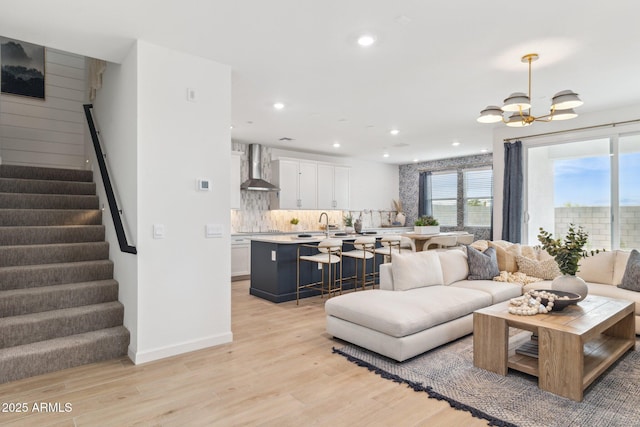 living room with light wood finished floors, recessed lighting, stairway, and an inviting chandelier