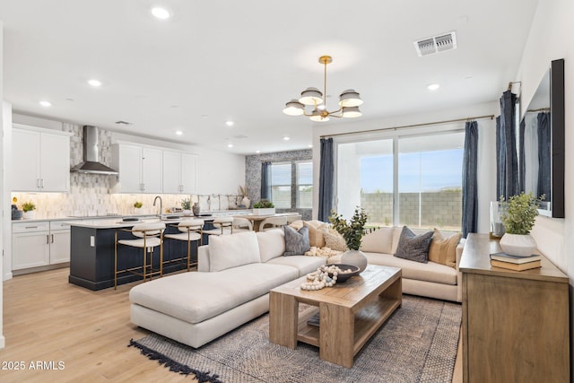 living area featuring light wood-type flooring, visible vents, a notable chandelier, and recessed lighting