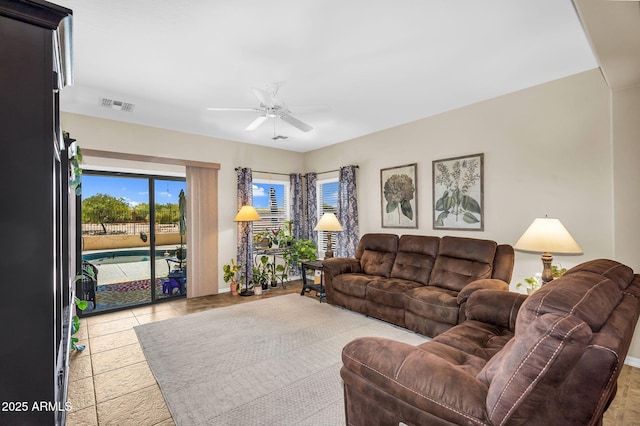 living area featuring ceiling fan, visible vents, and a healthy amount of sunlight