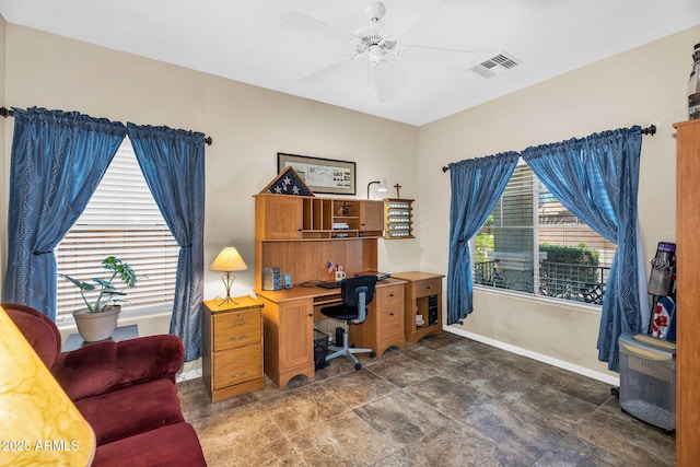 office area with baseboards, ceiling fan, stone finish floor, and visible vents