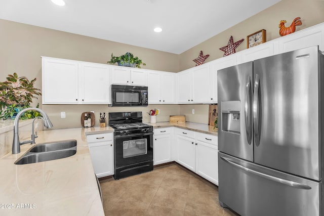 kitchen with a sink, white cabinetry, light tile patterned floors, and black appliances