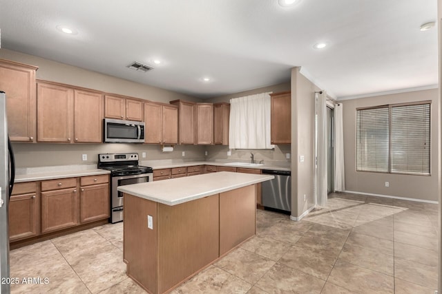 kitchen with stainless steel appliances, ornamental molding, a kitchen island, and sink