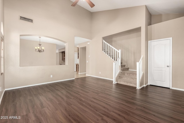 unfurnished living room with high vaulted ceiling, ceiling fan with notable chandelier, and dark hardwood / wood-style flooring