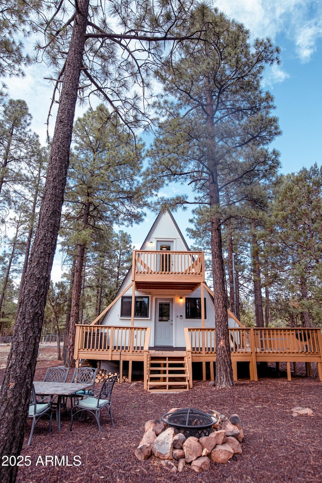 rear view of property with a balcony, a fire pit, and a deck