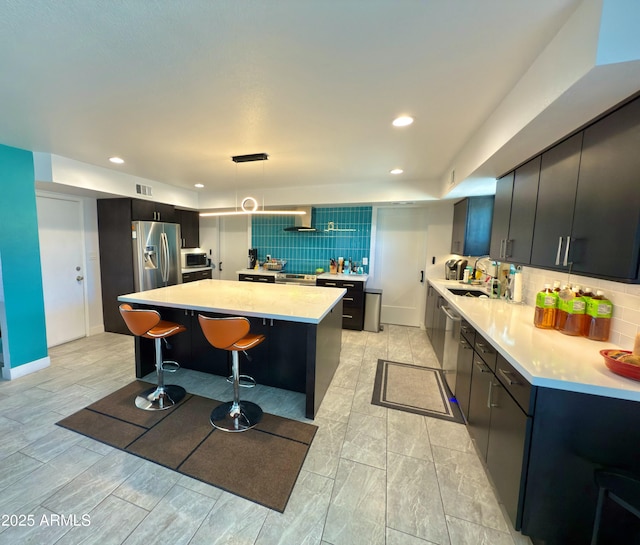 11035 N 37th St, Phoenix, AZ 85028 - kitchen featuring stainless steel appliances, a breakfast bar area, backsplash, light countertops, and a kitchen island