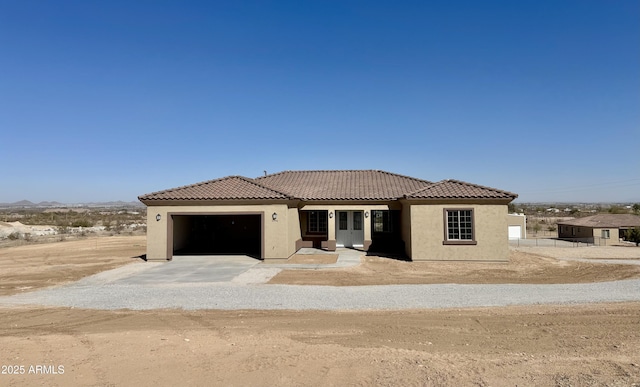 view of front of house featuring a garage, a tiled roof, driveway, and stucco siding