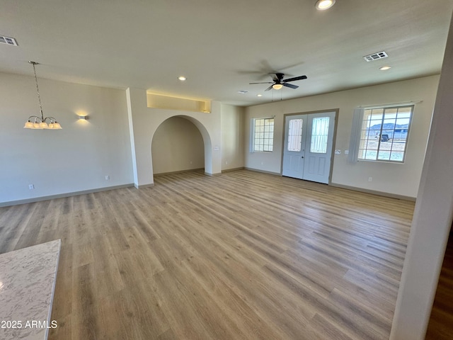 unfurnished living room with light wood finished floors, recessed lighting, visible vents, baseboards, and ceiling fan with notable chandelier