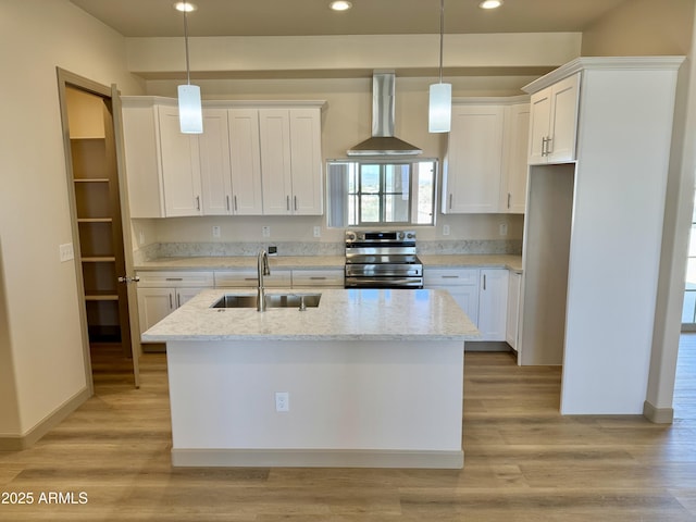 kitchen with stainless steel electric range oven, light wood finished floors, white cabinets, a sink, and wall chimney exhaust hood