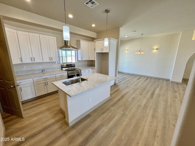 kitchen with a sink, visible vents, wall chimney range hood, stainless steel electric range oven, and light wood finished floors