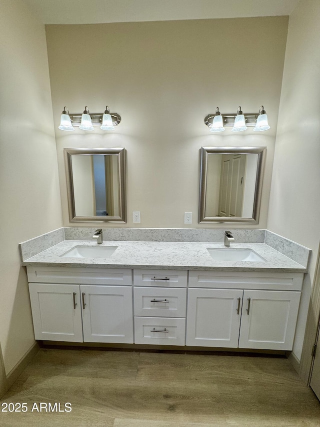 full bathroom with double vanity, a sink, and baseboards