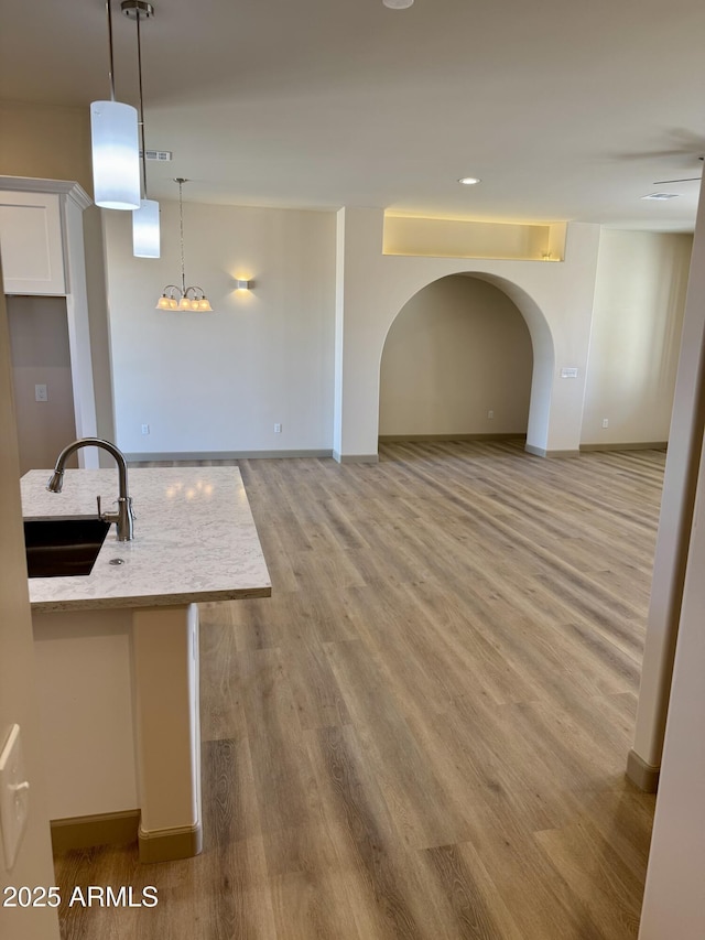 kitchen with white cabinetry, open floor plan, a sink, and wood finished floors