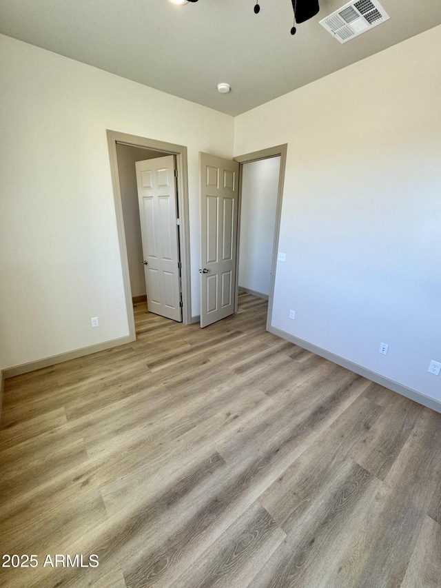 unfurnished bedroom with light wood-style flooring, visible vents, and baseboards