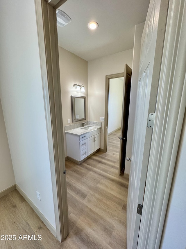 bathroom featuring wood finished floors, vanity, and baseboards