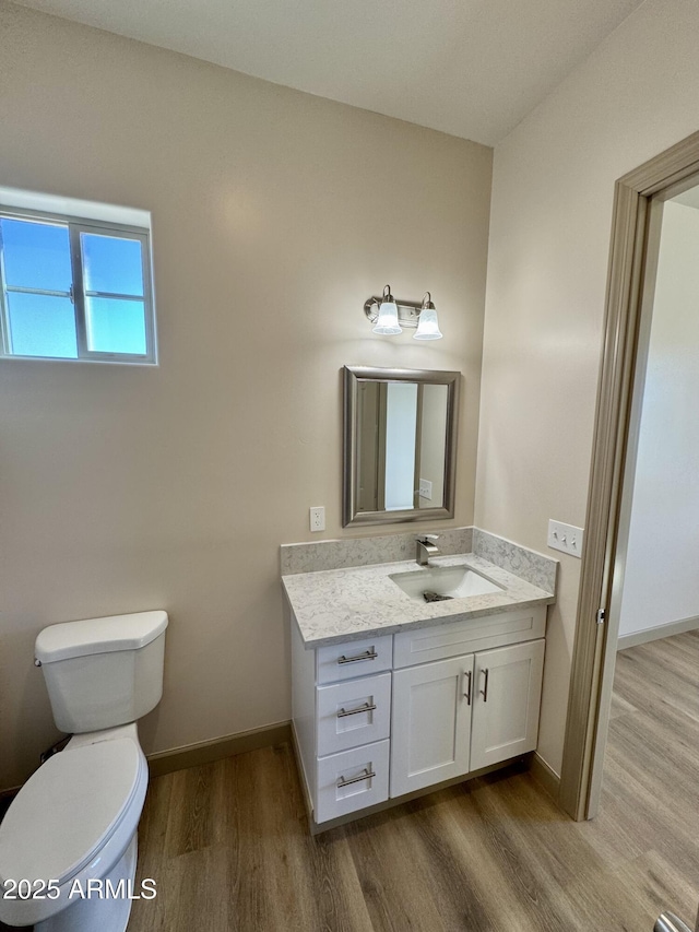 bathroom with baseboards, vanity, toilet, and wood finished floors