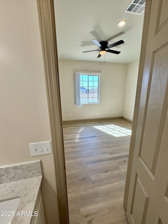 unfurnished room with light wood-type flooring, baseboards, visible vents, and a ceiling fan