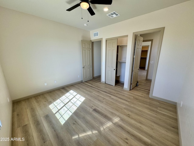 unfurnished bedroom featuring light wood-type flooring, a closet, visible vents, and baseboards