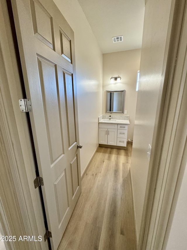 bathroom featuring visible vents, vanity, baseboards, and wood finished floors