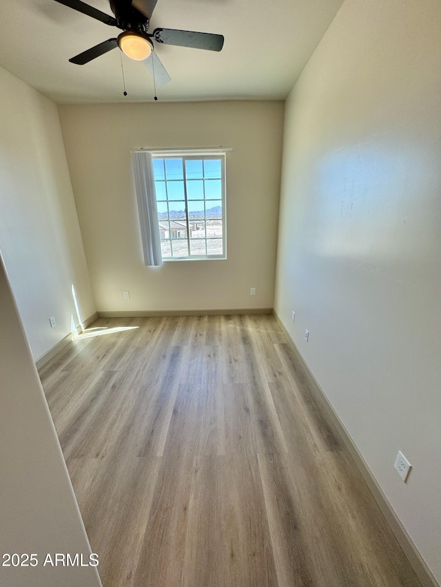 unfurnished room featuring a ceiling fan, baseboards, and wood finished floors