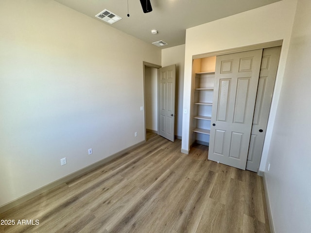 unfurnished bedroom with light wood finished floors, baseboards, visible vents, and a closet