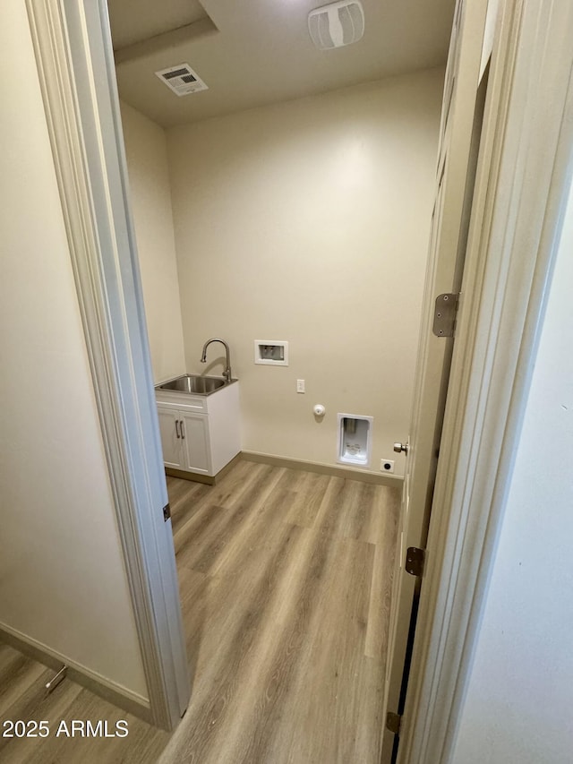 clothes washing area with washer hookup, hookup for a gas dryer, cabinet space, light wood-style flooring, and a sink