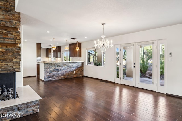 unfurnished living room featuring an inviting chandelier, french doors, dark hardwood / wood-style floors, and a healthy amount of sunlight