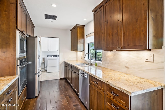 kitchen featuring light stone counters, dark hardwood / wood-style flooring, appliances with stainless steel finishes, independent washer and dryer, and sink