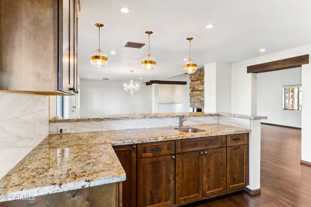 kitchen with pendant lighting, light stone countertops, sink, and kitchen peninsula