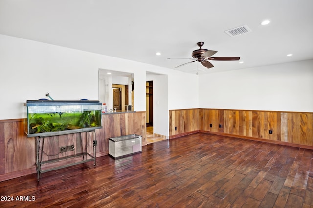 interior space featuring ceiling fan, dark hardwood / wood-style flooring, and wooden walls