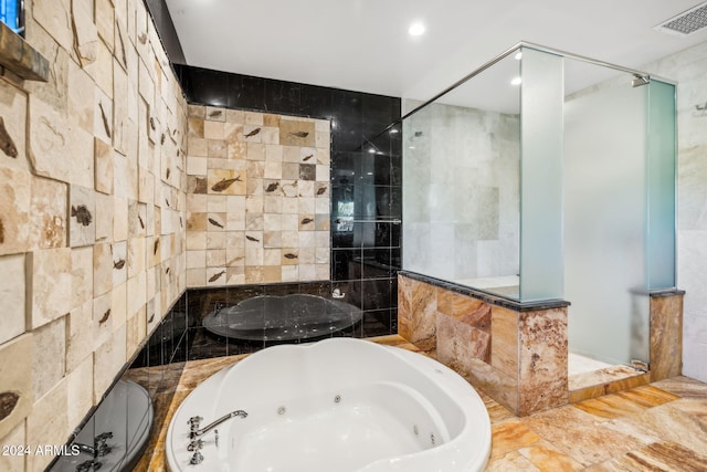 bathroom with tile walls and shower with separate bathtub