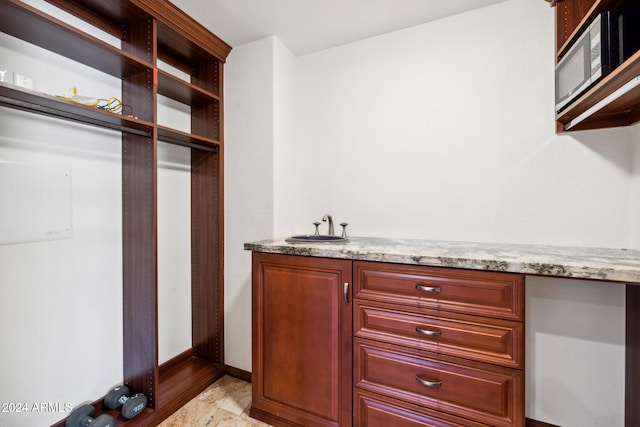 spacious closet with built in desk, sink, and light wood-type flooring