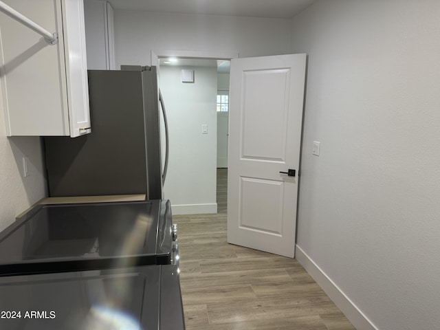 kitchen featuring white cabinets, stainless steel refrigerator, and light hardwood / wood-style floors