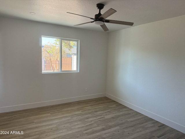 spare room with light wood-type flooring, a textured ceiling, and ceiling fan