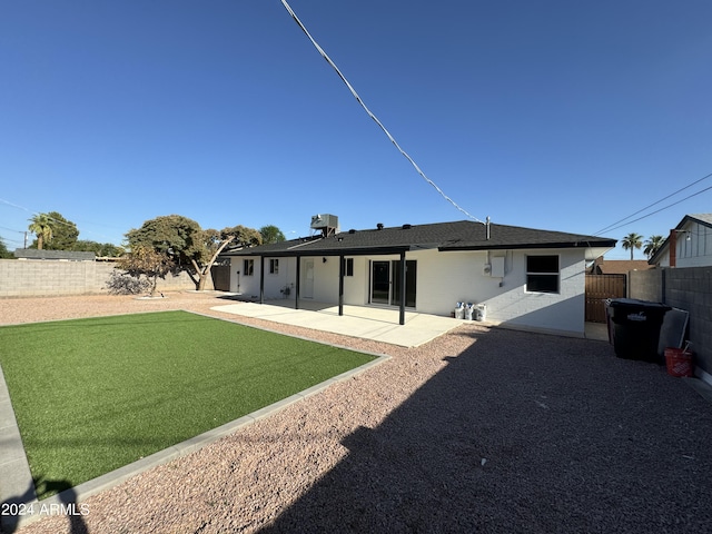 rear view of house with a patio and a lawn