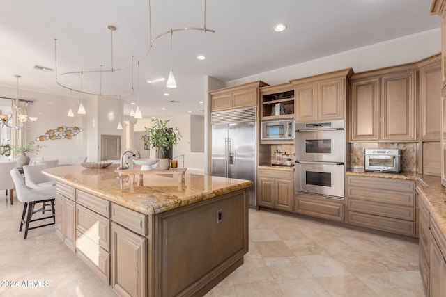 kitchen with decorative backsplash, light stone counters, built in appliances, decorative light fixtures, and a large island