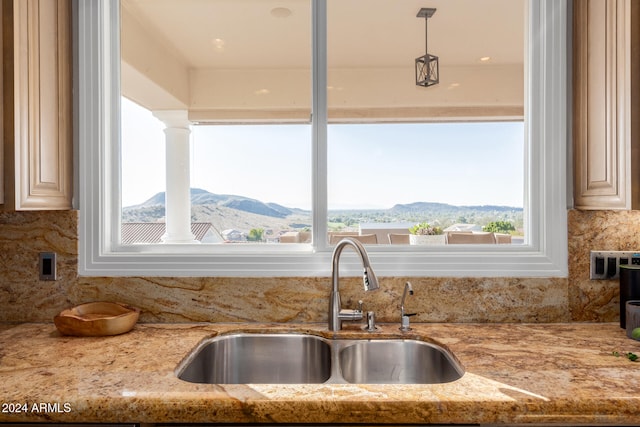 kitchen featuring a mountain view, light stone counters, sink, and tasteful backsplash