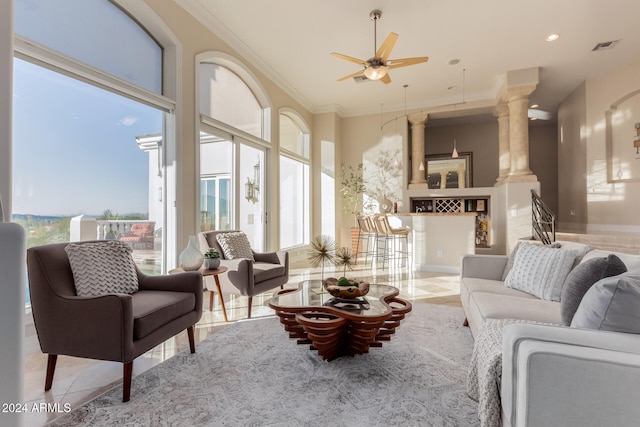 tiled living room featuring ornate columns, ceiling fan, and ornamental molding