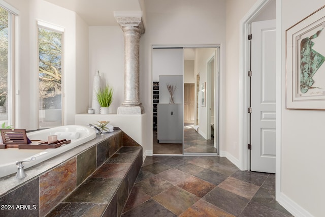 bathroom with tiled bath and decorative columns