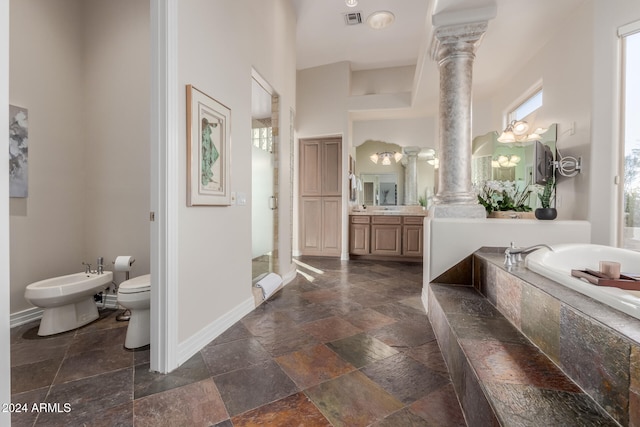 bathroom featuring a tub to relax in, ornate columns, vanity, a bidet, and toilet