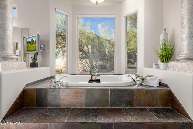 bathroom featuring a relaxing tiled tub and plenty of natural light