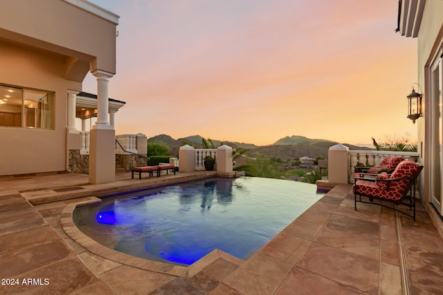 pool at dusk featuring a mountain view and a patio area