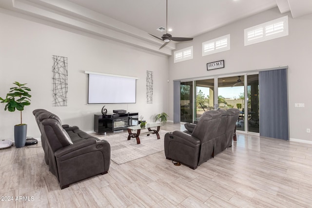 living room featuring a high ceiling, light wood-type flooring, and ceiling fan